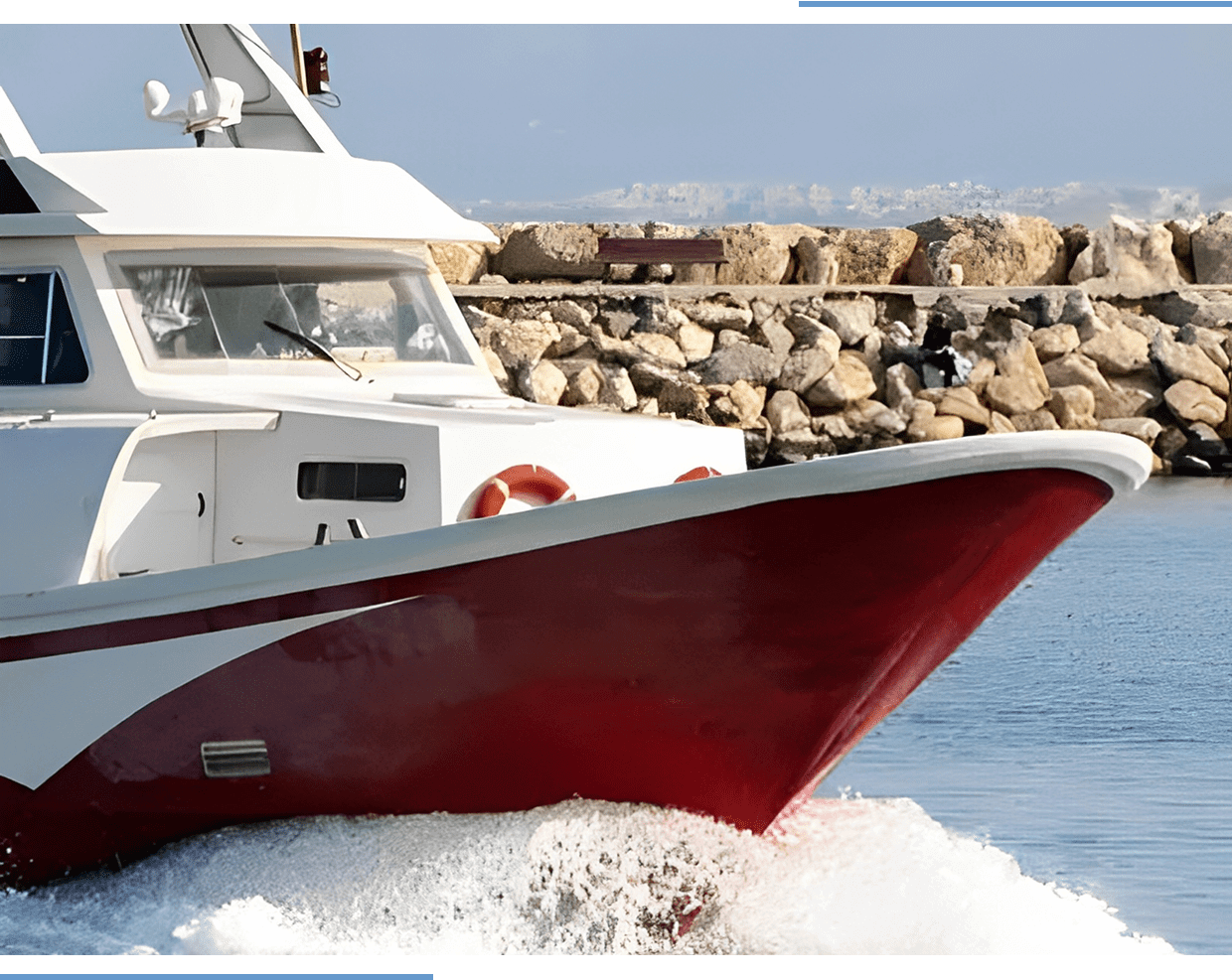 Red and white boat near rocky shore.